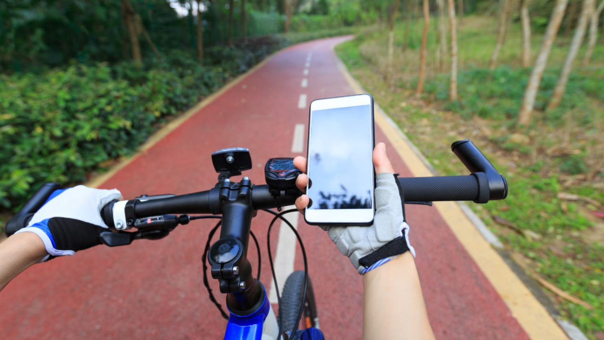 A first person point-of-view image of a cyclist tracking distance on their phone.