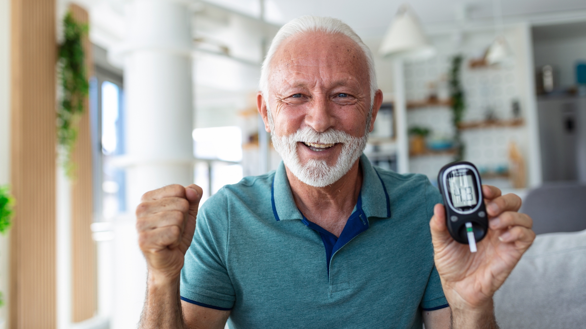 An older man excitedly holds a glucometer. It reads 4,8.